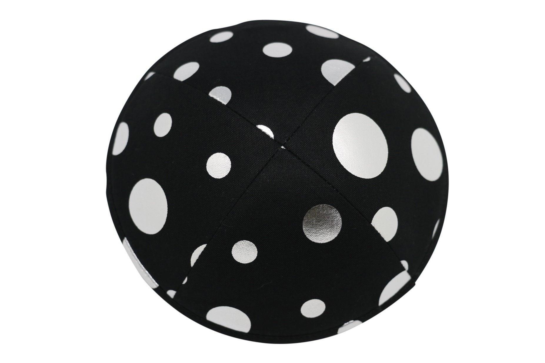 A black iKIPPAJH brand yarmulke with a number of bright silver circles on it top view.